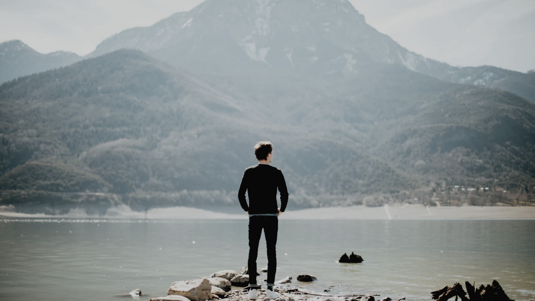Man standing in front of a mountain staring off in the distance
